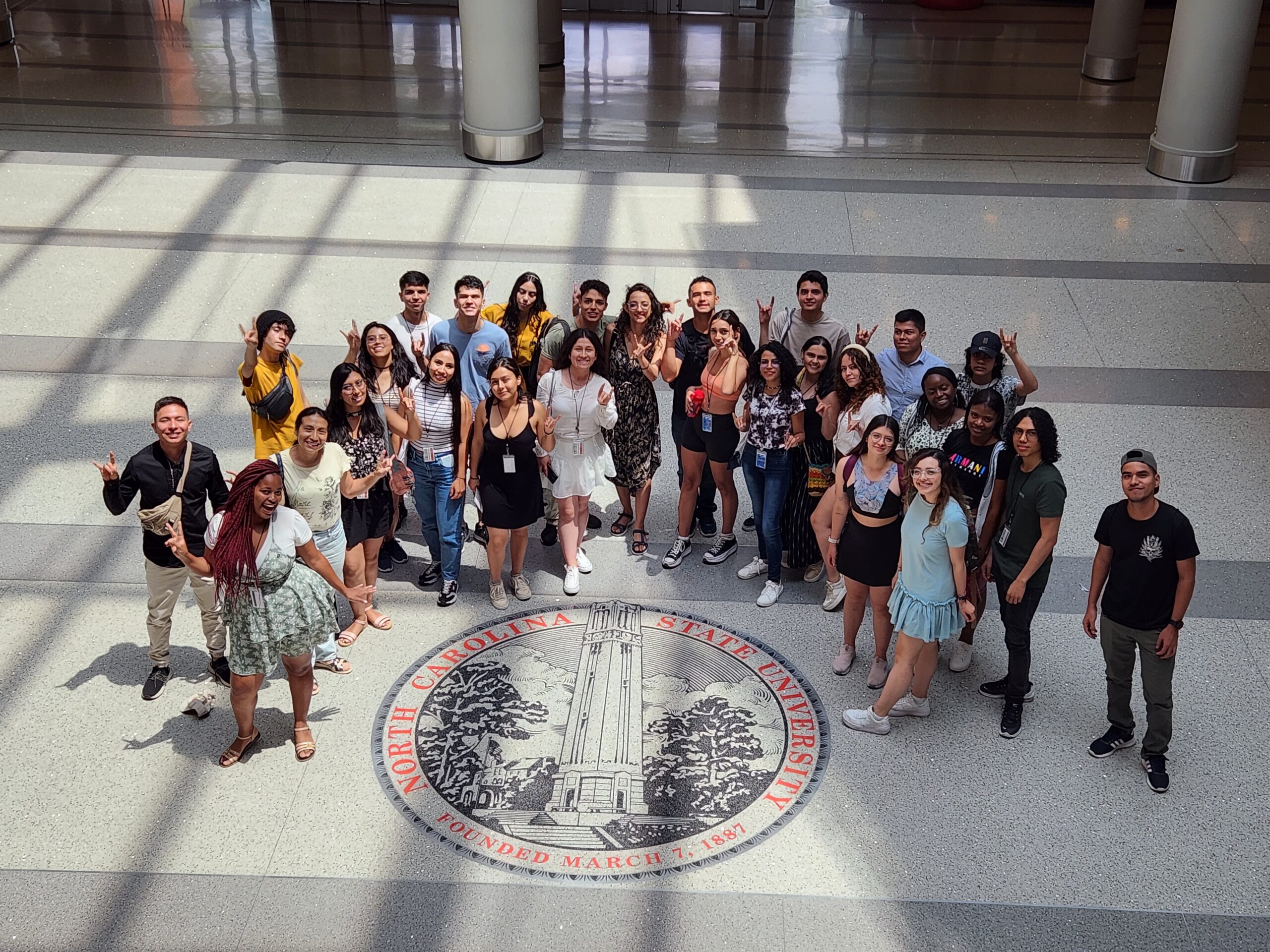 group of Colombian students standing around the NC State seal in Talley Student Union