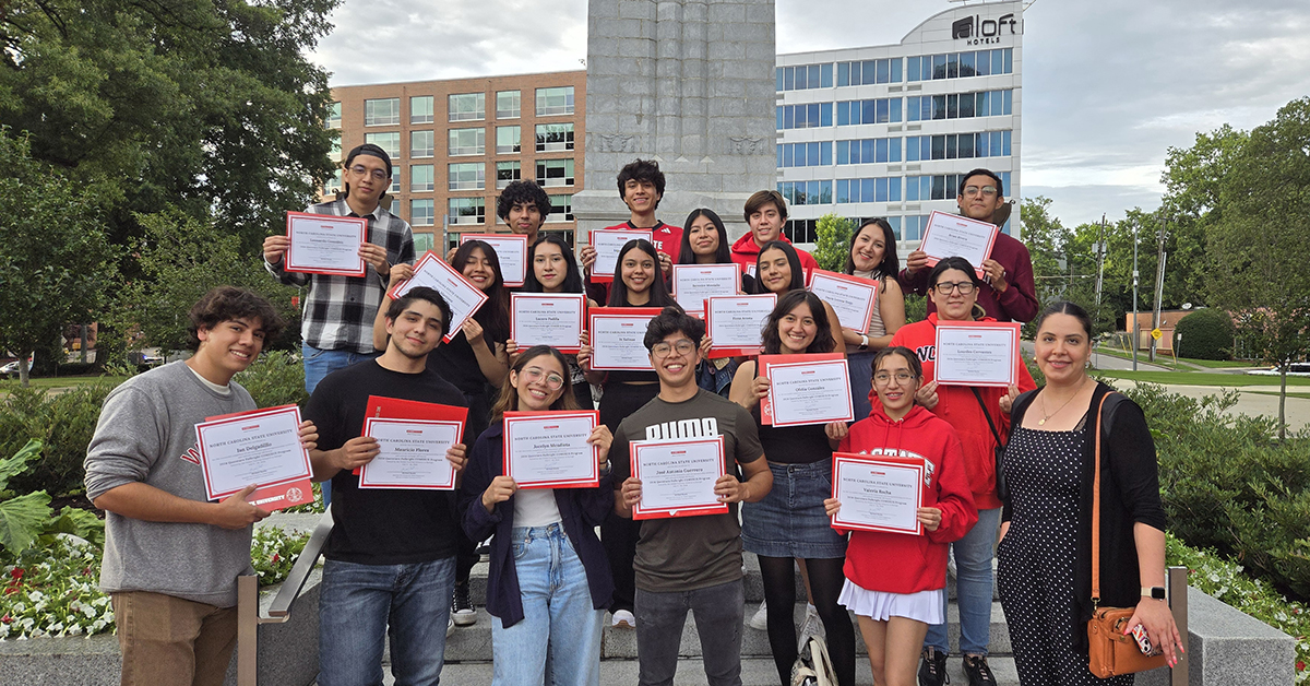 students holding certificates in front of Belltower